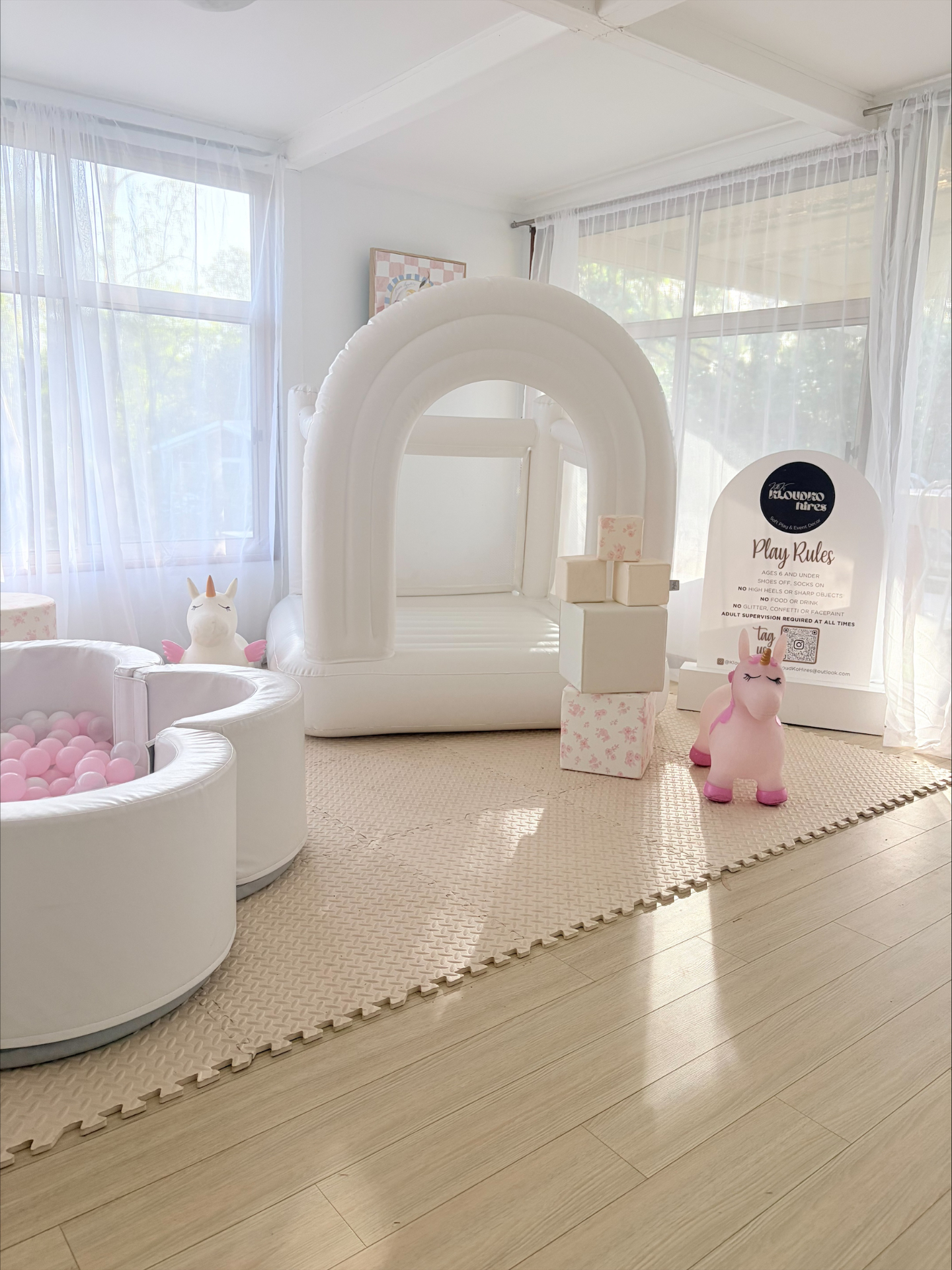 White bounce house and pink ball pit soft play setup styled indoors.